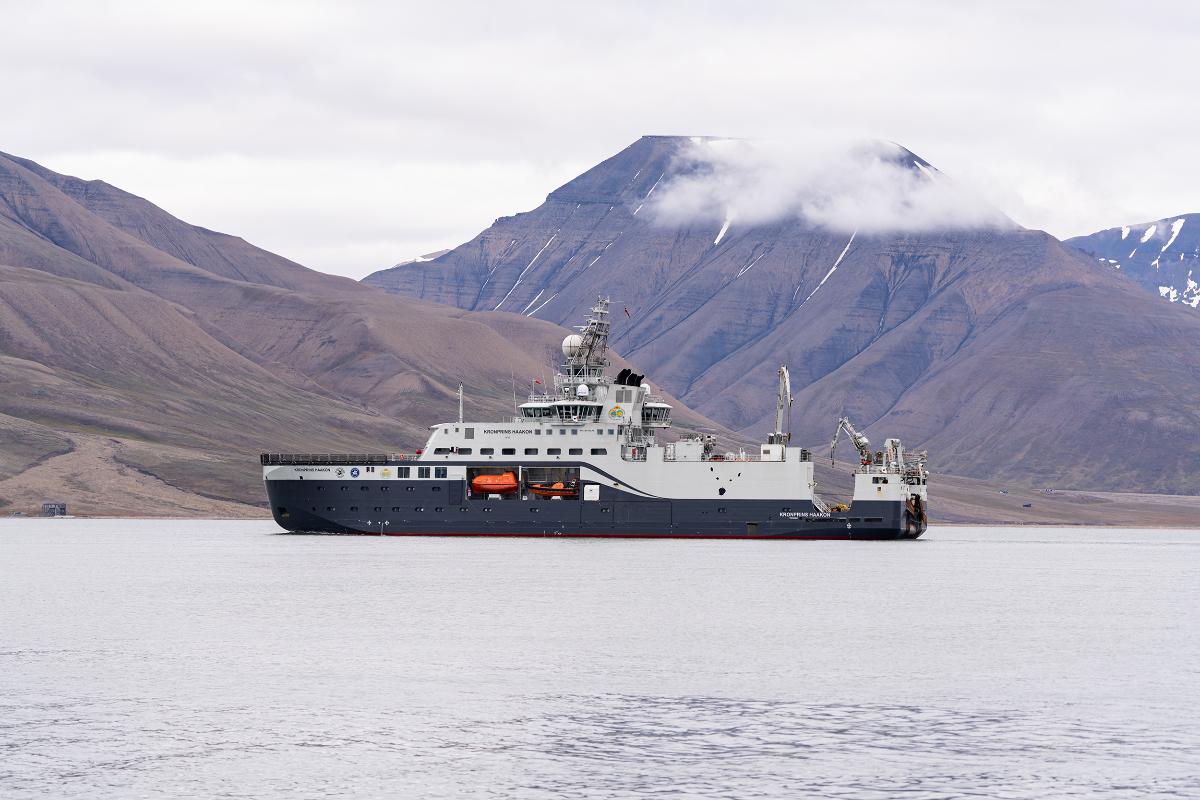 konrpins haakon kph ved svalbard foto Ingrid Ballari Nilssen.jpg et skip i en rolig fjord, nakne fjell i bakgrunnen
